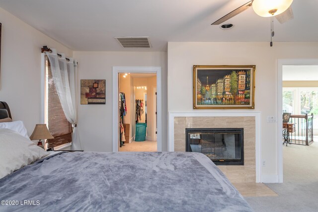 bedroom with ceiling fan, a fireplace, and light colored carpet