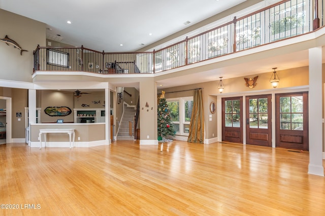 unfurnished living room featuring light hardwood / wood-style flooring, plenty of natural light, and a high ceiling