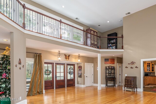 entrance foyer featuring a towering ceiling and light wood-type flooring