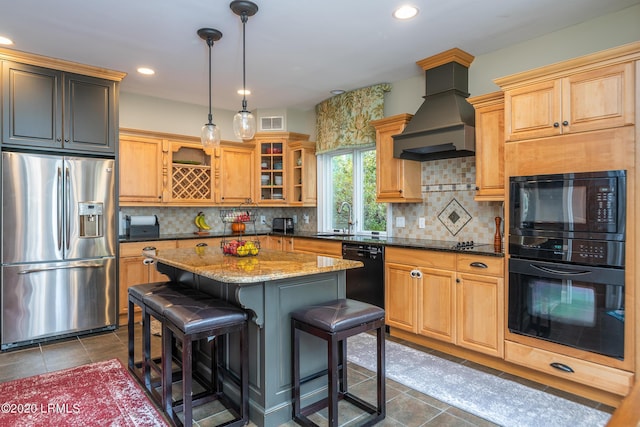 kitchen with hanging light fixtures, light stone counters, black appliances, a kitchen island, and custom exhaust hood