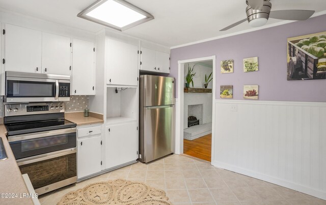 kitchen with light tile patterned flooring, white cabinetry, crown molding, stainless steel appliances, and decorative backsplash