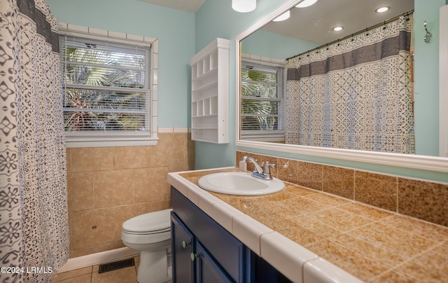 bathroom featuring tile patterned flooring, vanity, tile walls, and toilet