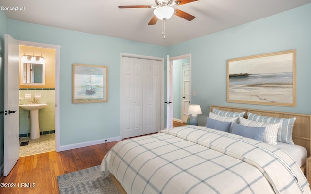 bedroom with ensuite bathroom, hardwood / wood-style floors, sink, ceiling fan, and a closet