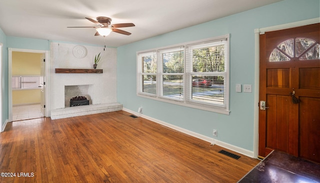 unfurnished living room featuring ceiling fan, wood-type flooring, and a fireplace