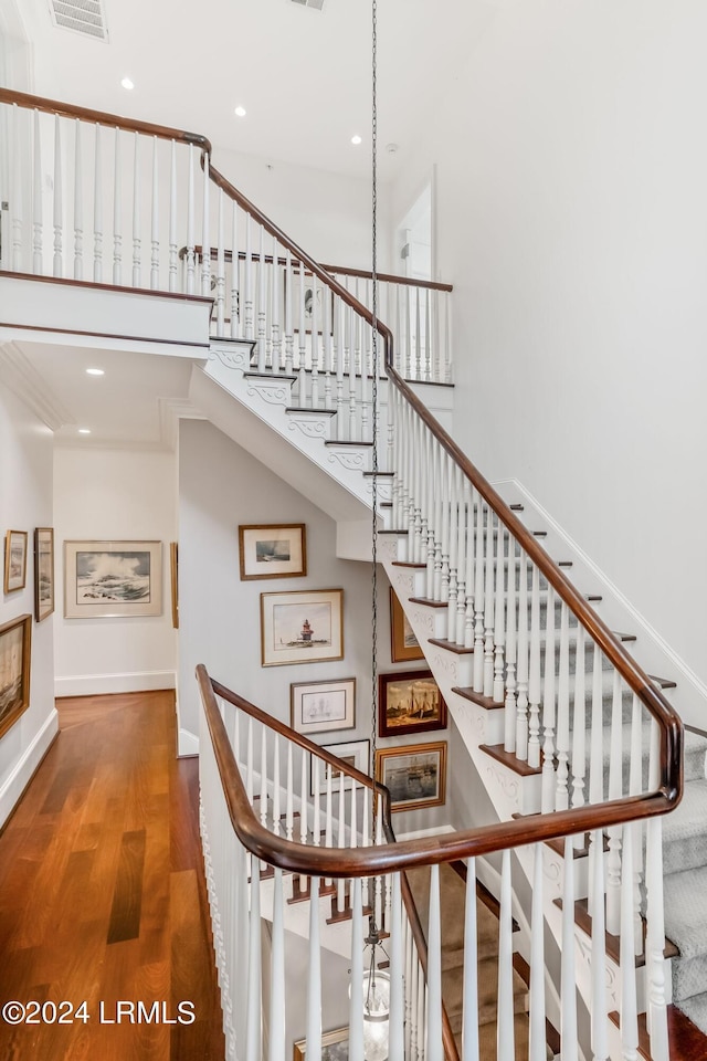 stairway featuring wood-type flooring and a high ceiling