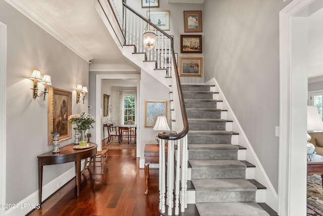 staircase with hardwood / wood-style floors and ornamental molding