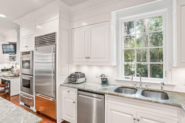 kitchen with white cabinetry, stainless steel appliances, sink, and light stone counters