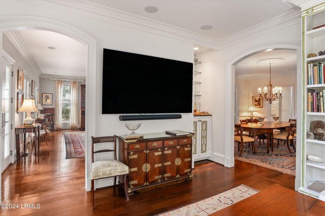 living room featuring ornamental molding, dark hardwood / wood-style flooring, built in features, and a notable chandelier