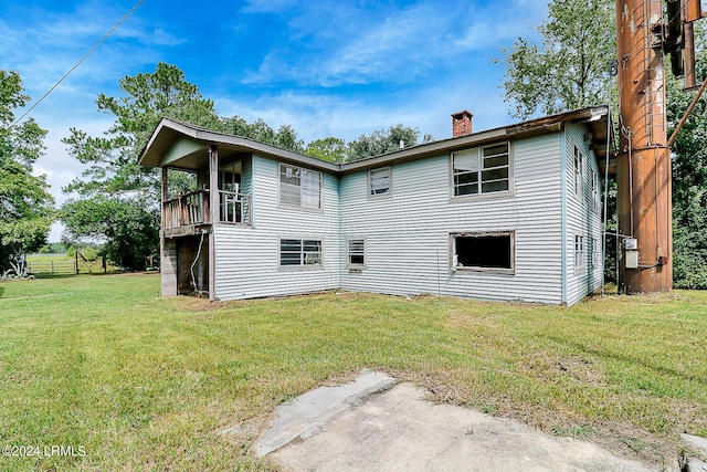 rear view of house featuring a balcony and a yard