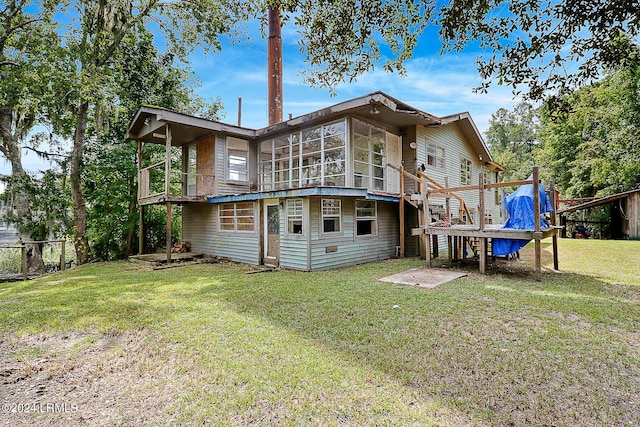 back of house with a yard, a deck, and a sunroom