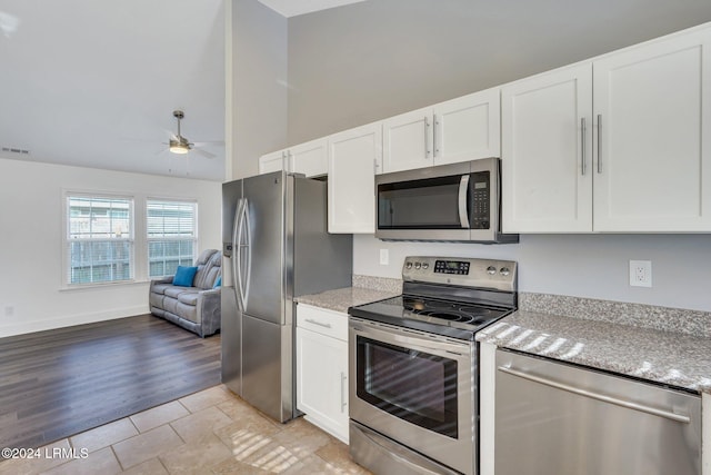 kitchen featuring light tile patterned floors, ceiling fan, white cabinetry, stainless steel appliances, and light stone counters