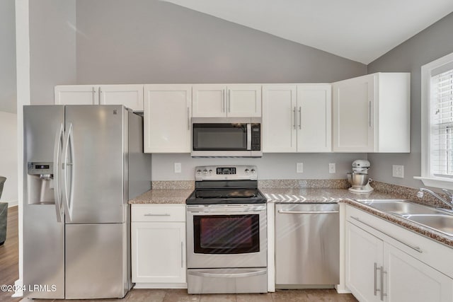 kitchen featuring lofted ceiling, sink, plenty of natural light, stainless steel appliances, and white cabinets