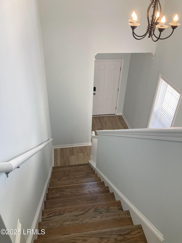 stairs featuring hardwood / wood-style flooring and an inviting chandelier