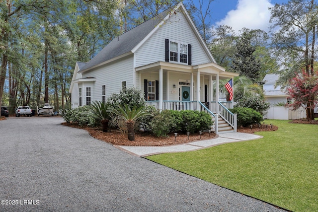 view of front facade featuring gravel driveway, a porch, a shingled roof, a front yard, and fence