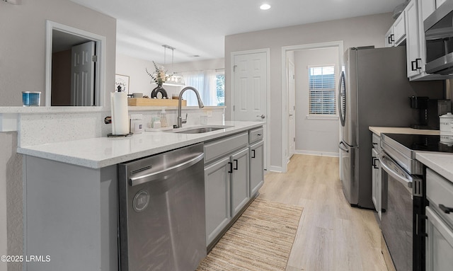 kitchen with sink, gray cabinets, light hardwood / wood-style floors, and appliances with stainless steel finishes