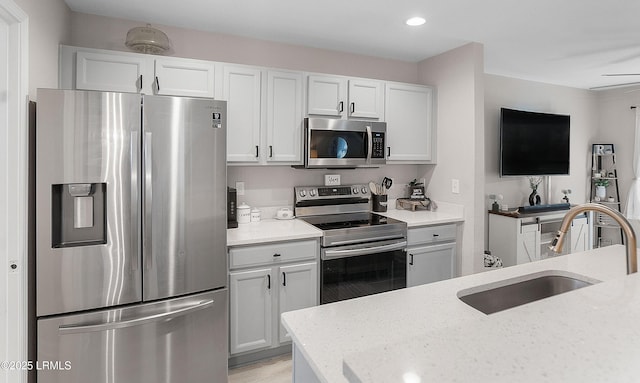 kitchen featuring sink, stainless steel appliances, white cabinets, and light stone countertops