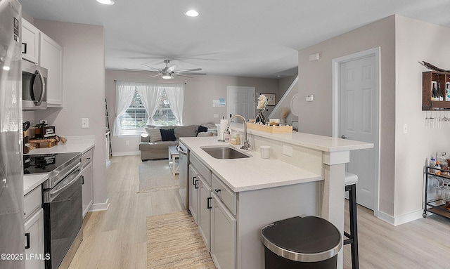 kitchen with sink, light hardwood / wood-style flooring, a breakfast bar area, a kitchen island with sink, and stainless steel appliances