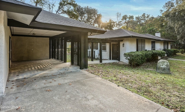 100 Thomas Sumter St, Beaufort, SC 29907 - view of property exterior featuring driveway, an attached carport, stucco siding, a chimney, and a lawn