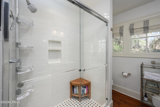 bathroom with hardwood / wood-style flooring, toilet, and a shower with shower door