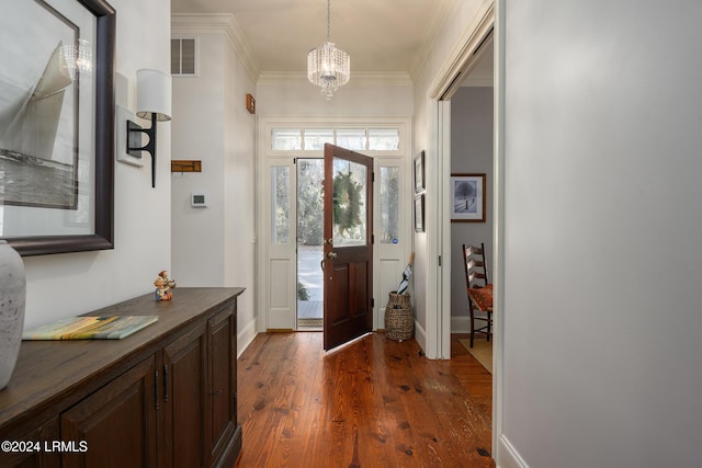 entryway with crown molding, dark hardwood / wood-style floors, and an inviting chandelier