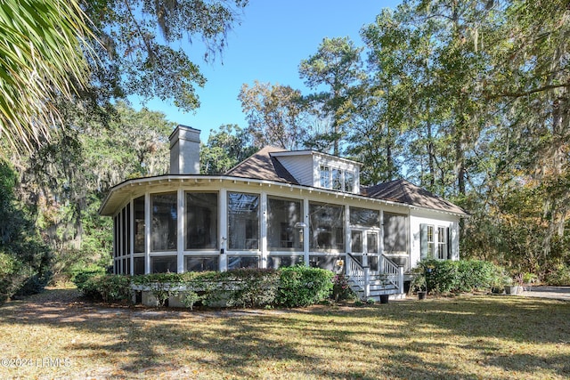 rear view of house featuring a sunroom and a lawn