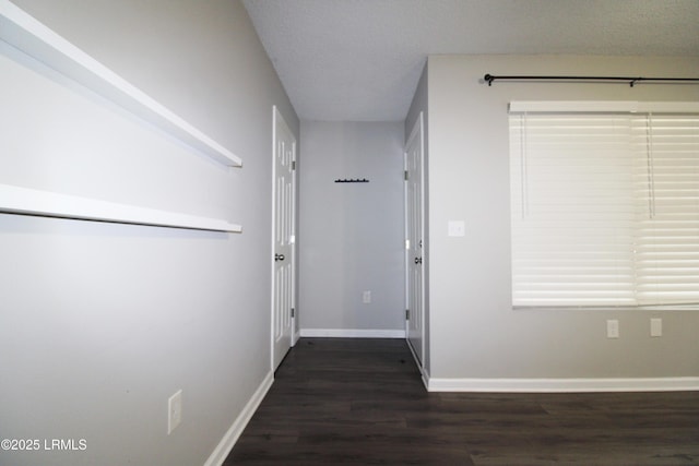 corridor with baseboards, a textured ceiling, and dark wood-style flooring