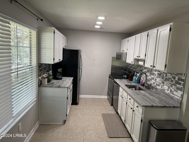 kitchen featuring sink, light stone counters, appliances with stainless steel finishes, decorative backsplash, and white cabinets