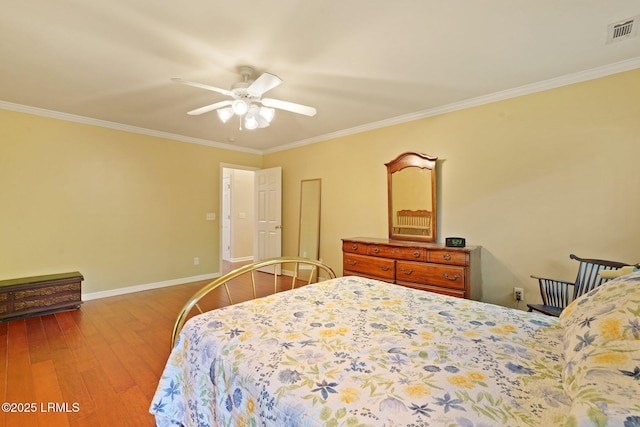 bedroom featuring crown molding, visible vents, baseboards, and wood finished floors