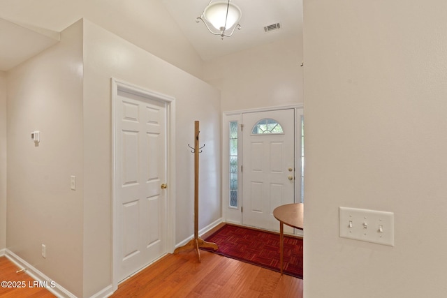 foyer with visible vents, baseboards, and parquet flooring