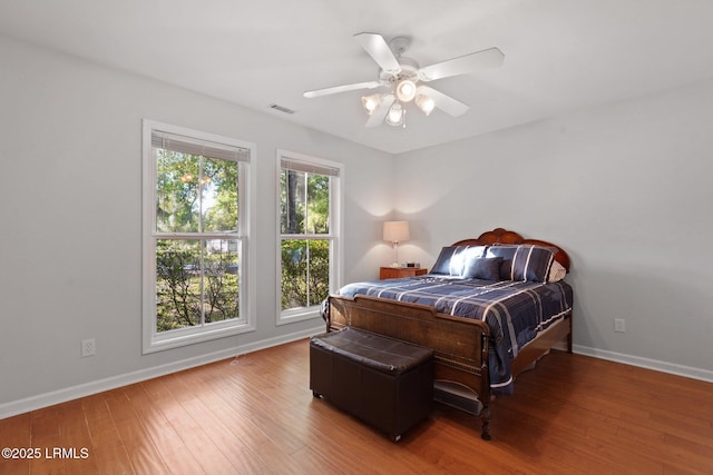 bedroom with visible vents, baseboards, a ceiling fan, and wood finished floors