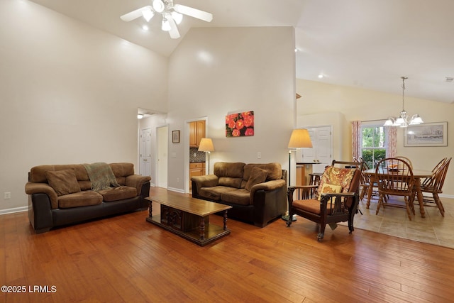 living area with wood-type flooring, baseboards, vaulted ceiling, and ceiling fan with notable chandelier