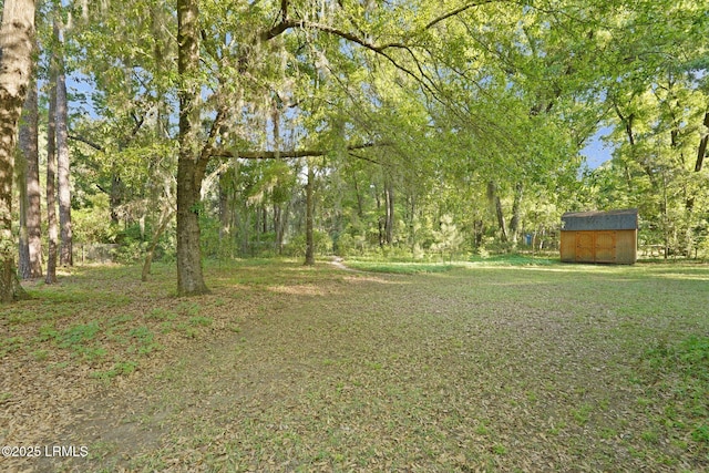 view of yard featuring a view of trees, a shed, and an outdoor structure
