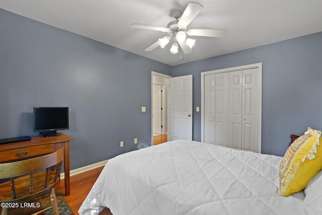 bedroom featuring wood finished floors, a closet, a ceiling fan, and baseboards