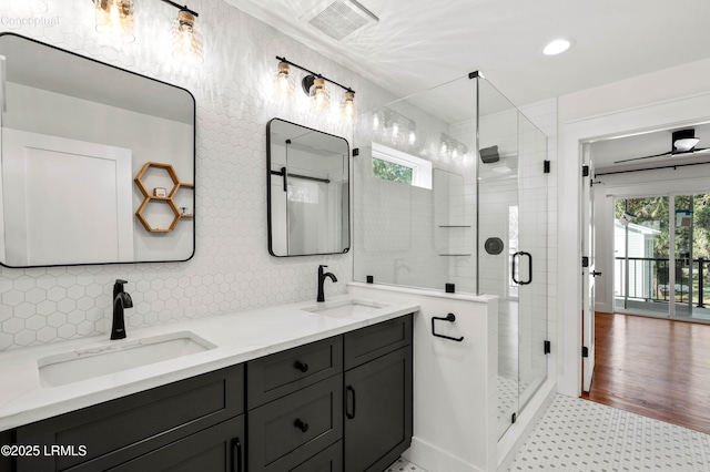 bathroom with decorative backsplash, a sink, visible vents, and a shower stall