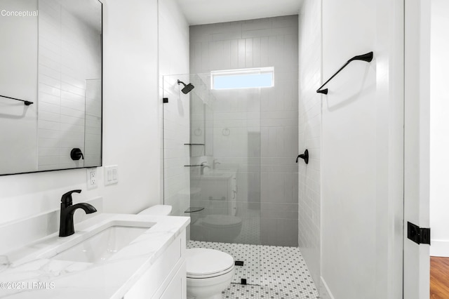 bathroom featuring toilet, tiled shower, and vanity