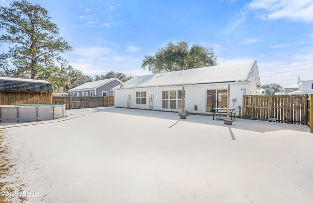 rear view of property with a fenced in pool and a patio