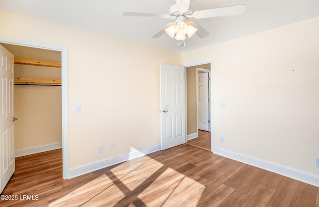 unfurnished bedroom with ceiling fan, a spacious closet, light hardwood / wood-style floors, and a closet