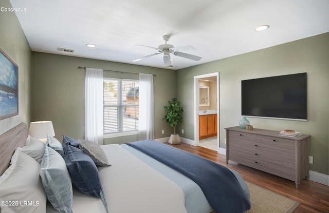 bedroom featuring connected bathroom, dark wood-type flooring, and ceiling fan