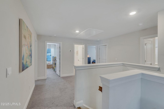 hallway featuring recessed lighting, light colored carpet, attic access, an upstairs landing, and baseboards