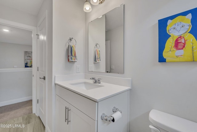 half bathroom with toilet, baseboards, and vanity