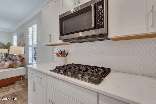 kitchen featuring appliances with stainless steel finishes, white cabinets, and ornamental molding