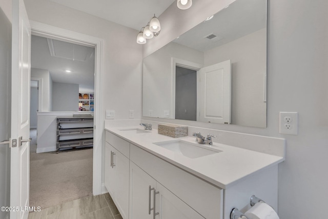 bathroom featuring visible vents, a sink, a spacious closet, and double vanity