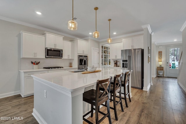 kitchen featuring stainless steel appliances, light wood-type flooring, white cabinets, and an island with sink