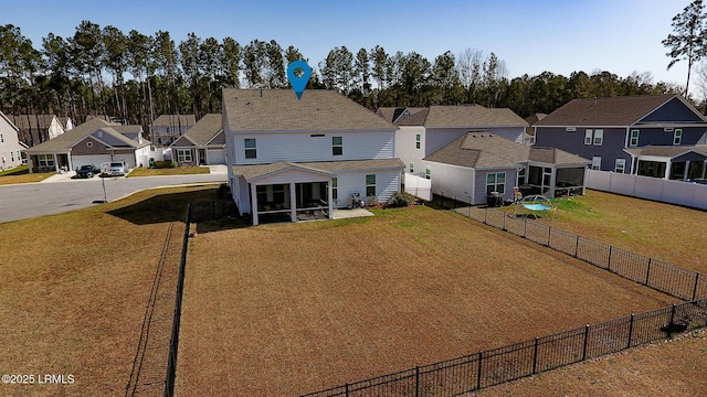 exterior space with a sunroom, a fenced backyard, a residential view, and a yard