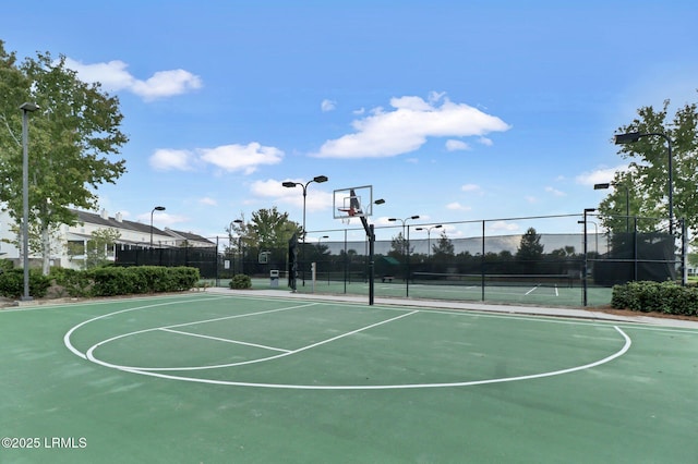 view of basketball court with a tennis court, community basketball court, and fence