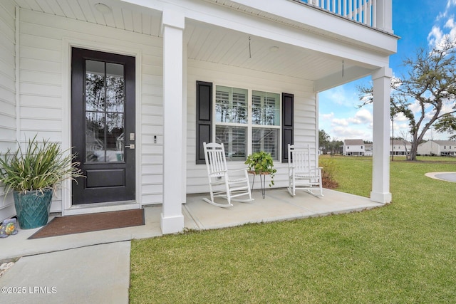 view of exterior entry with a yard and a porch