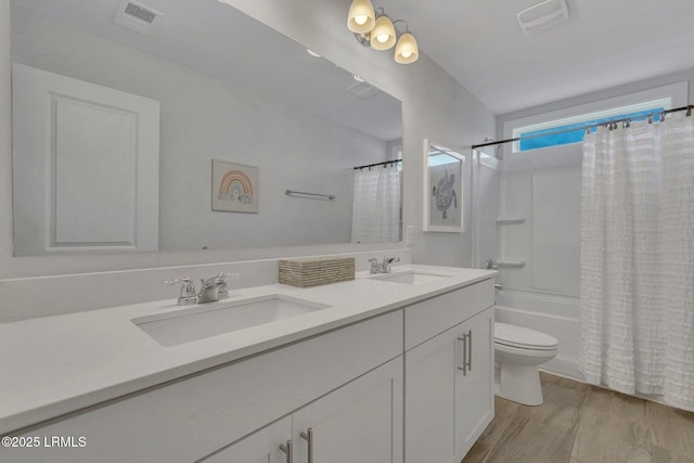 bathroom with toilet, double vanity, visible vents, and a sink