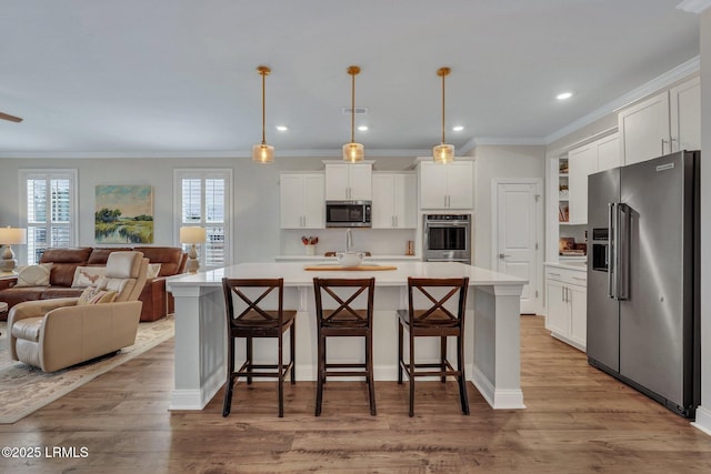 kitchen with stainless steel appliances, wood finished floors, white cabinets, open floor plan, and light countertops