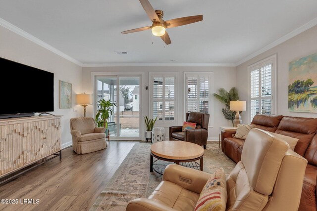 living room featuring baseboards, visible vents, crown molding, and wood finished floors