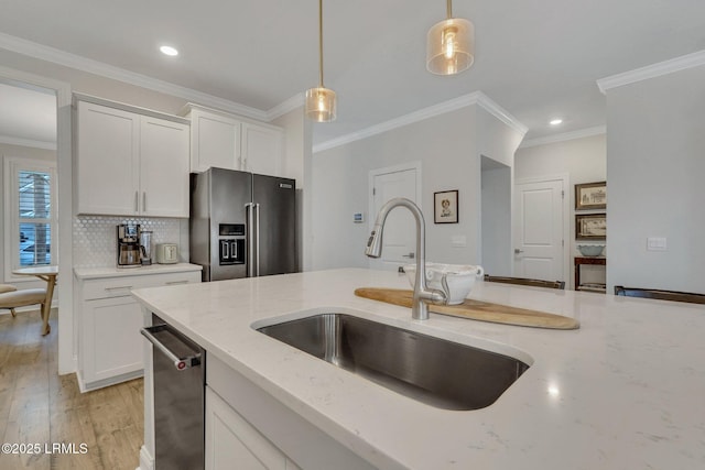 kitchen featuring light stone counters, hanging light fixtures, appliances with stainless steel finishes, white cabinets, and a sink